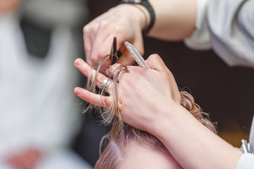 Close-up of a hairdresser woman cutting hair in beauty salon