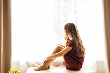 Cute teenager girl sitting near window