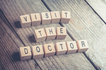 Closeup Of A Visit The Doctor Reminder Formed By Wooden Blocks On A Wooden Floor