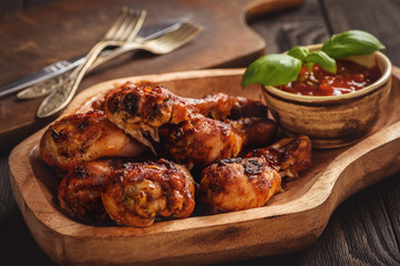 Oven baked chicken drumsticks on wooden tray.