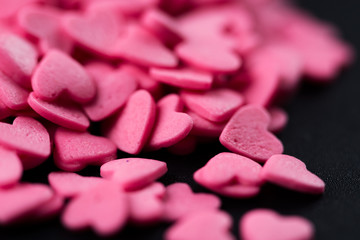 Pink hearts on a black background. Close-up.