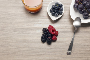 Fresh berries on a wooden table with a glass of juice. Antioxidants, detox diet, organic fruits.