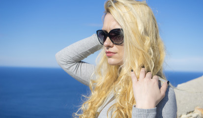 Happiness Summer vacation young blonde with long hair and happy sunglasses near mediterranean sea