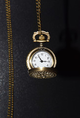 Hanging Ornamented Vintage Pocket Watch on Black Background 