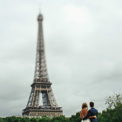 Fototapeta na wymiar Hugging wedding couple stands before the Eiffel tower in Paris