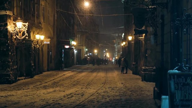 Snow-covered night street in the old town Lviv, Ukraine. Evening street of the old city, it's snowing.
