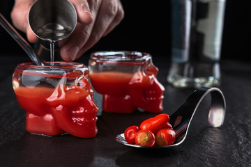 Preparing shots of bloody Mary in a glass in the shape of a skull.