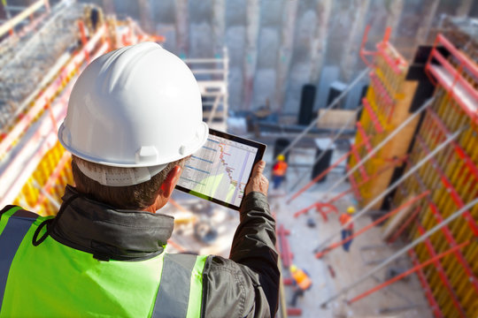 civil engineer or architect on construction site checking schedule with tablet computer