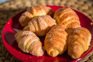 Homemade freshly baked croissants on red plate. Closeup