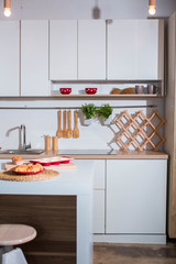 Modern white kitchen. On table in red plate lie croissants