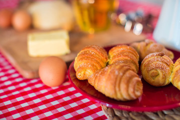 Fresh homemade croissants on red plate on the background of ingredients for making cookies