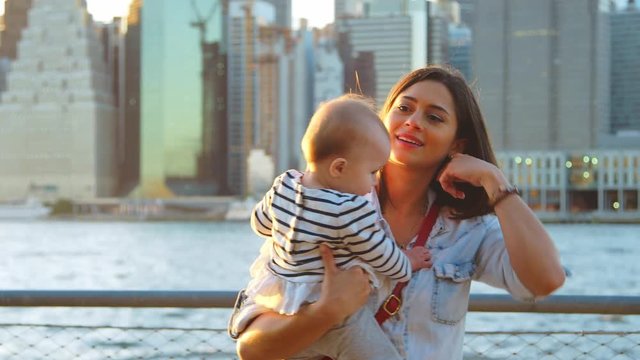 Young mother with daughter standing at riverside, Manhattan