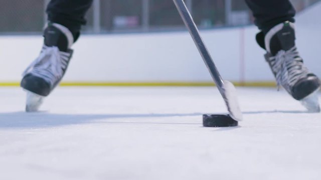 Cinematic action shot of a young male hockey player standing on skates and stick handling with a puck