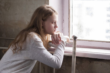 Depressed young girl sitting in the abandoned building.