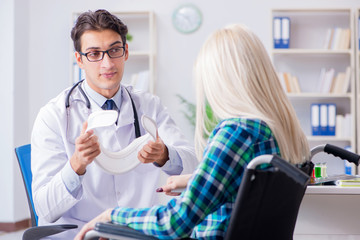 Fototapeta premium Disabled woman in wheel chair visiting man doctor