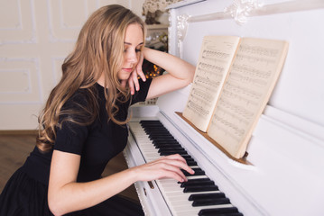 young blond woman play no white piano