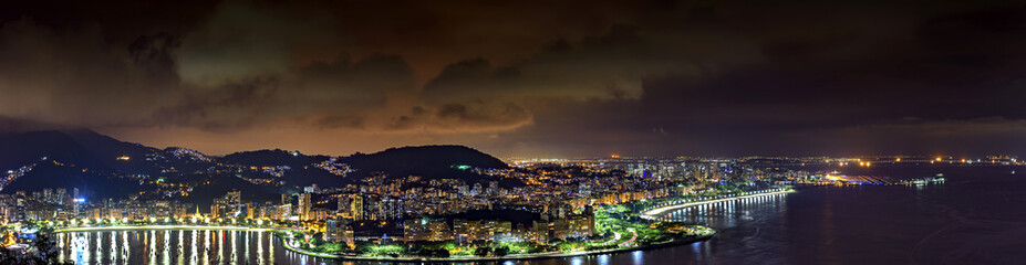 Fototapeta na wymiar Panoramic image of Rio de Janeiro seen from above at night with its lights, hills, streets, Gaunabara bay and Santos Dumont airport