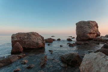 Coastal sunset landscape. Rocks & stones at the seashore.