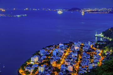 Night view of Urca neighborhood, Santos Dumont airport and Rio-Niteroi bridge in Rio de Janeiro with the city of Niteroi in the background.
