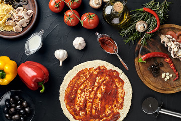 Raw pizza ingredients on black texture table background