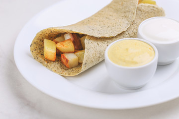 Vegetarian masala dosa with potato, chutney and sambar sauces.