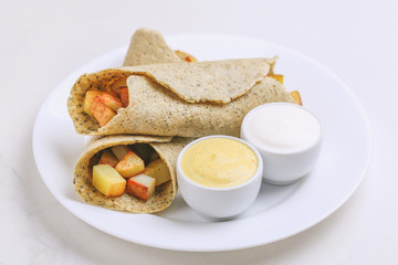 Vegetarian masala dosa with potato, chutney and sambar sauces.