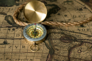 Fototapeta na wymiar Old compass on vintage map with rope