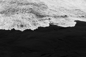 texture of dark stones contrasting with white foam of the waves