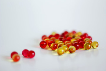 Yellow and red capsules with vitamin a and E on light background