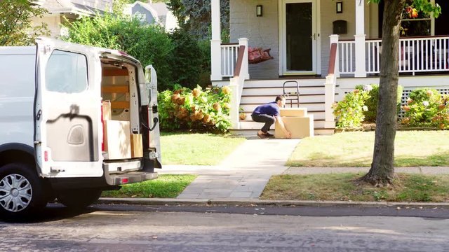 Courier Using Trolley To Deliver Package To House