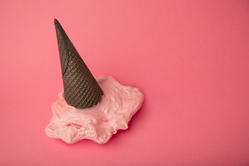 Overhead pink plastic ice cream on chocolate black cone on paste