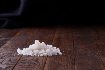Obraz na płótnie Canvas Pile of salt crystals on the dark wooden background, top view, flat lay, shallow depth of field