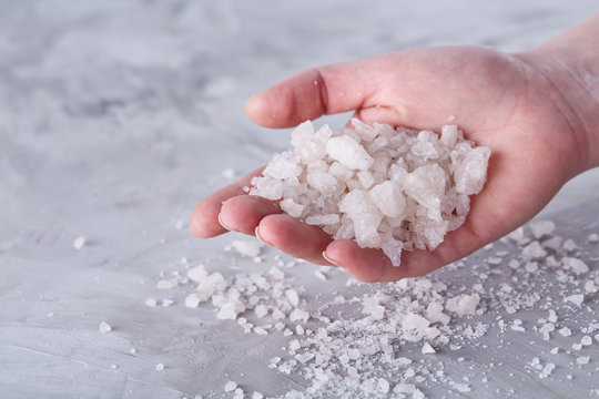 Sea Salt Crystals In Women Hand On White Background, Overhead, Close-up