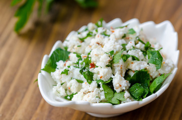 homemade curd cheese with parsley, and red pepper on a wooden table