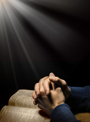 Hands folded in prayer over Scriptures © Marina
