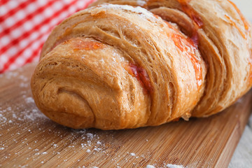 Tasty croissant on wooden board, closeup