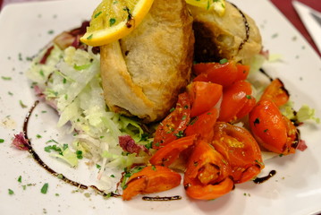 A dish of sicilian rolls, tomatoes and orange