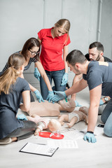 Group of people learning how to make first aid heart compressions with dummies during the training...