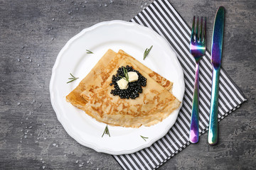 Thin pancakes with delicious black caviar and butter on plate