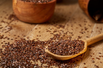 Wooden spoon with flax seeds on rustic background, top view, close-up, shallow depth of field, selective focus