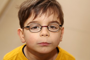 Junge mit Brille schaut traurig in die Kamera