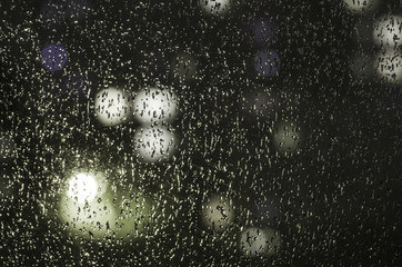 drops of rain on the window on the background of the night bokeh