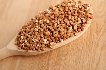 Close-up of buckwheat grains lie in a wooden spoon