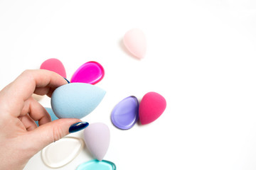 Female hand holding blue beauty sponge over a white background