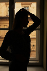 Naklejka premium Silhouette of slim model standing at the window