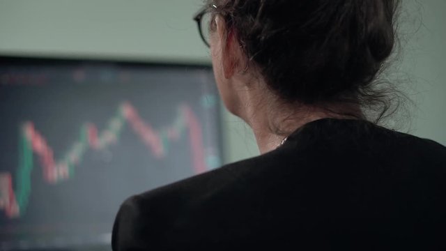 Mature woman brunette looks on monitor searching currency trend