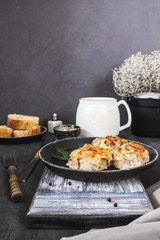 Baked cutlets with sour cream sauce, cheese, dill, smoked paprika, spices on a black pan.