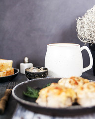 Baked cutlets under cheese and sour cream sauce, on a dark table top, close-up. deadpan.