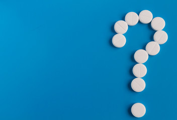 Question mark from white tablets on a blue background