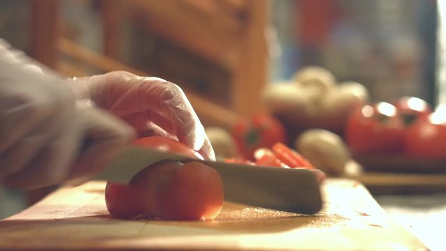 Cutting tomatoes on a cutting board.
Close-up. Slow motion. Focus in.
Female hands cut the tomato into slices.